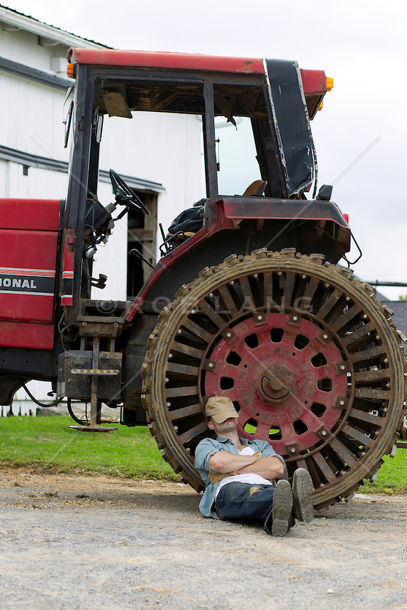 farm-worker-taking-a-break-to-rest-against-a-large-tractor-on-a-farm.jpg