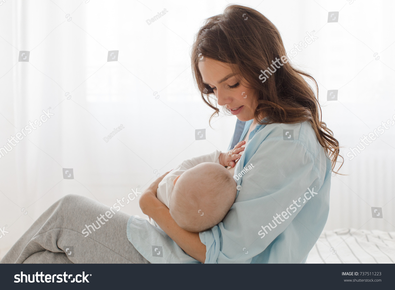 is-breastfeeding-a-baby-sitting-on-a-light-window-background-mother-breast-feeding-and-737511223.jpg