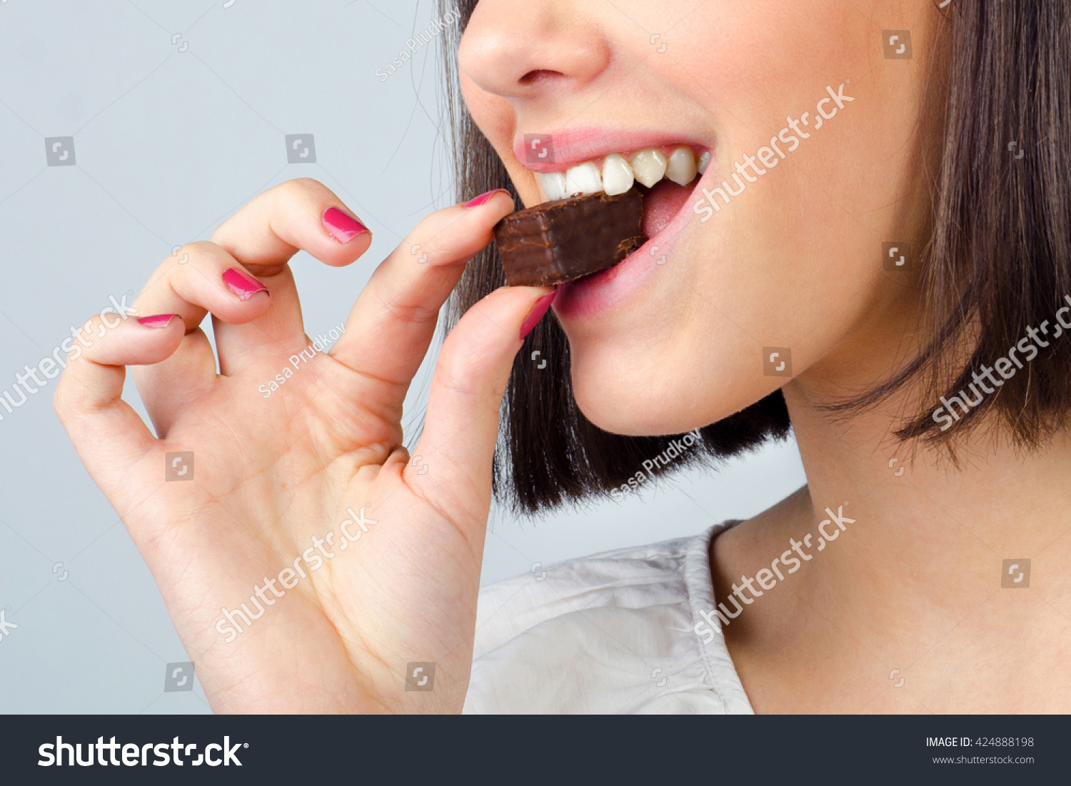 to-portrait-of-the-beautiful-girl-eating-chocolate-cookies-isolated-on-gray-background-424888198.jpg